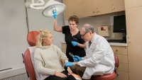 Dermatologist uses magnifying glass to diagnose acne and treat